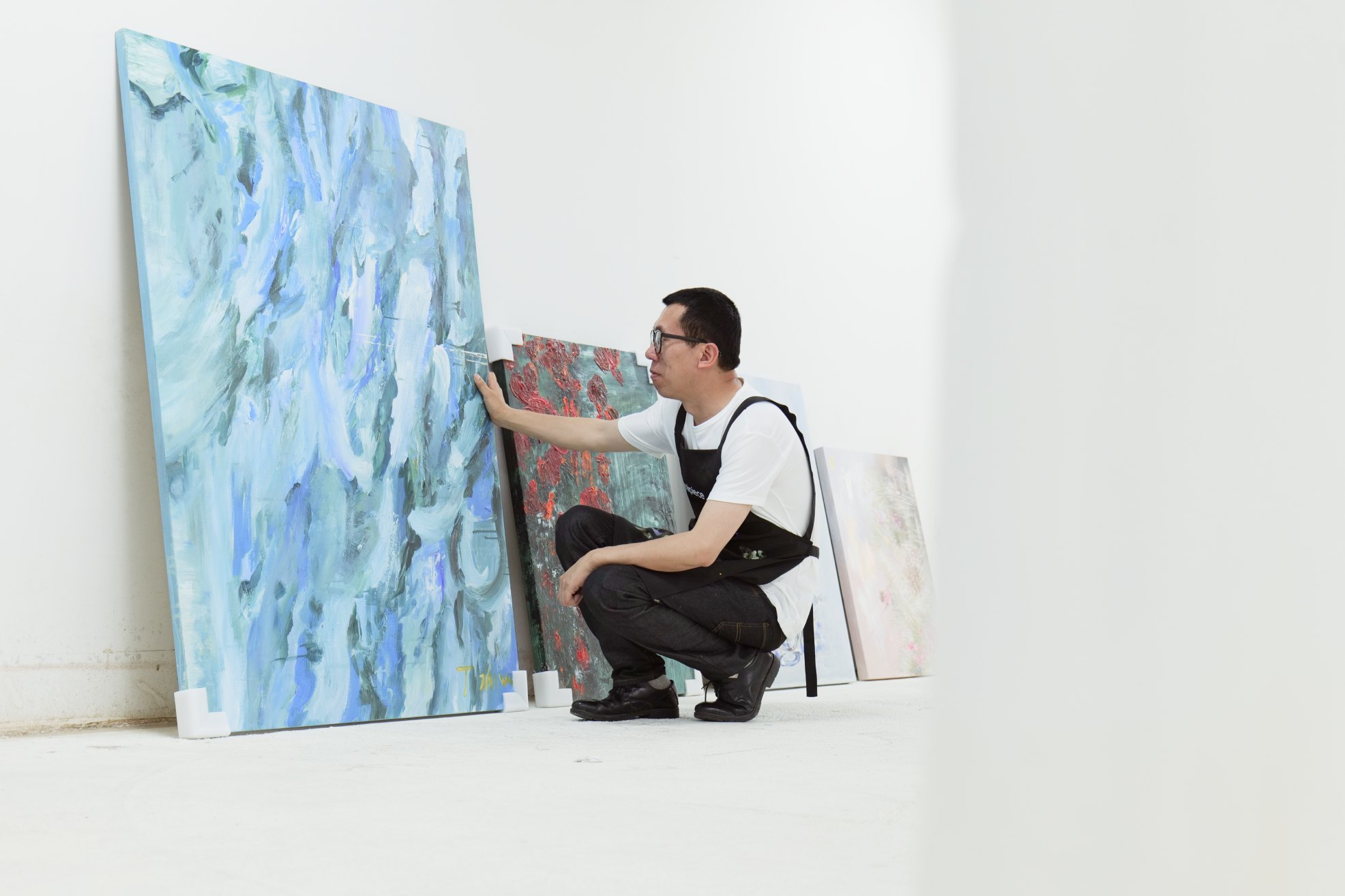An artist detailing large canvases